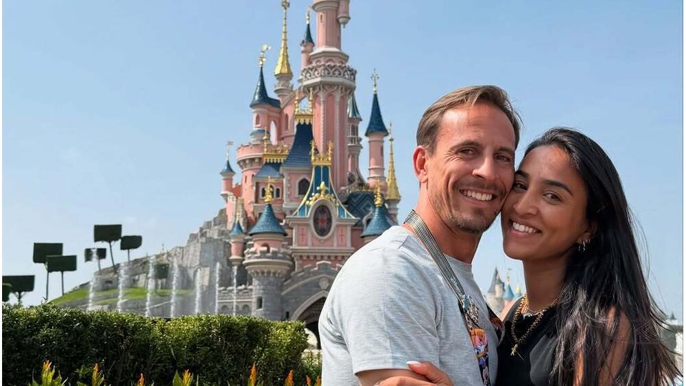 Casal sorri em frente ao castelo da Disneyland Paris