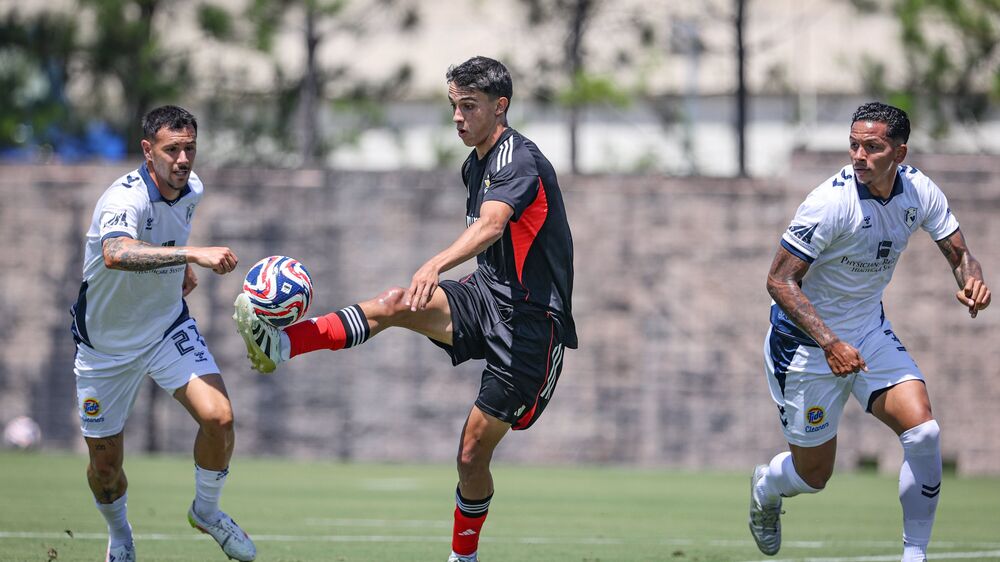 Futebolistas em campo disputam a posse da bola