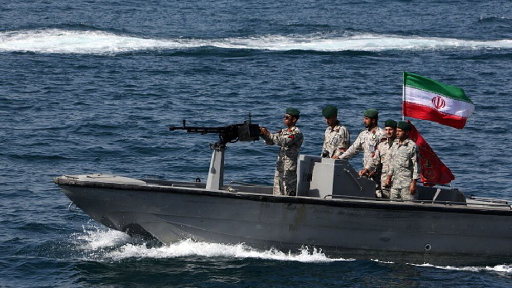 Militares iranianos em embarcação patrulham águas com a bandeira do Irão.

