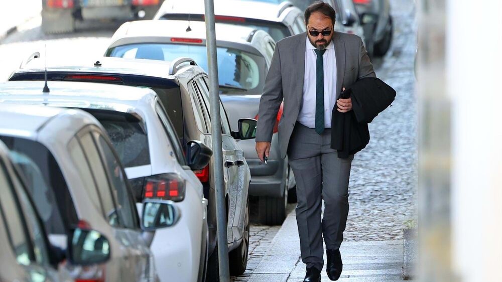 Um homem de fato e óculos de sol caminha na rua