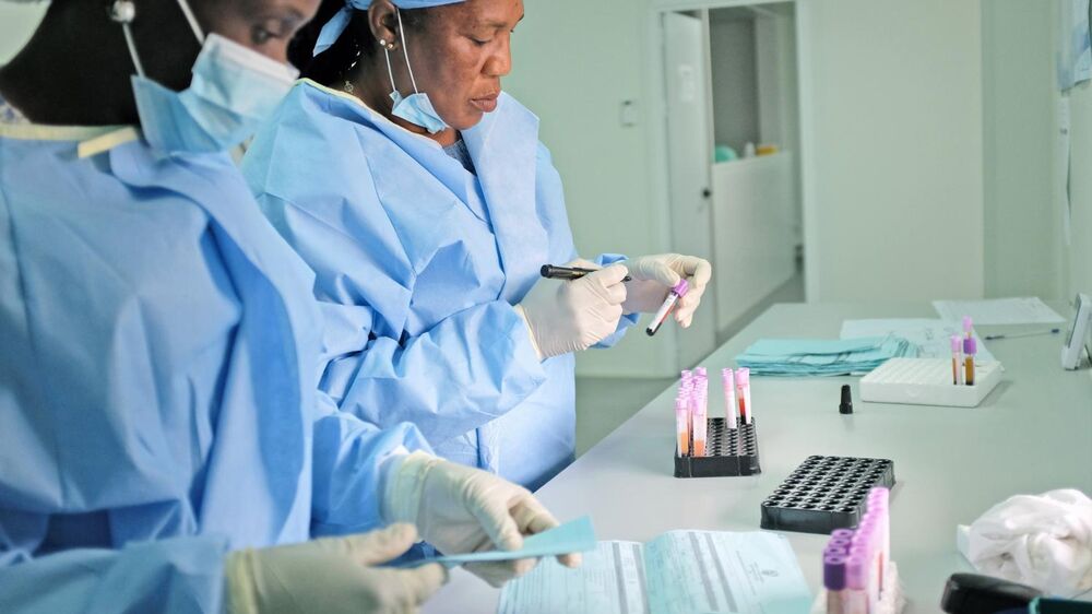 Técnicos de laboratório analisam amostras de sangue para monitorizar a progressão da sida