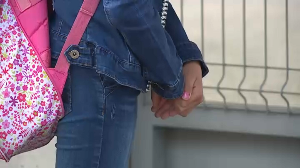 Uma criança com uma mochila florida veste uma jaqueta de ganga