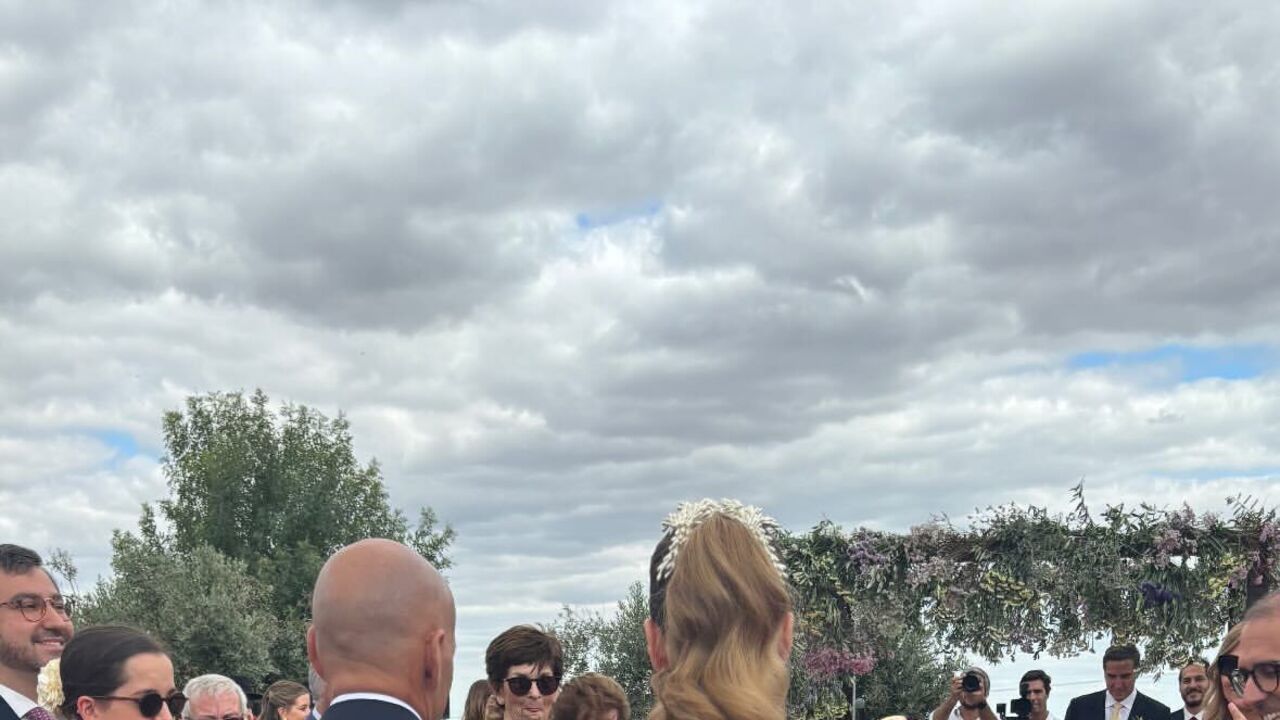 Noiva caminha para o altar, acompanhada, sob o olhar atento dos convidados