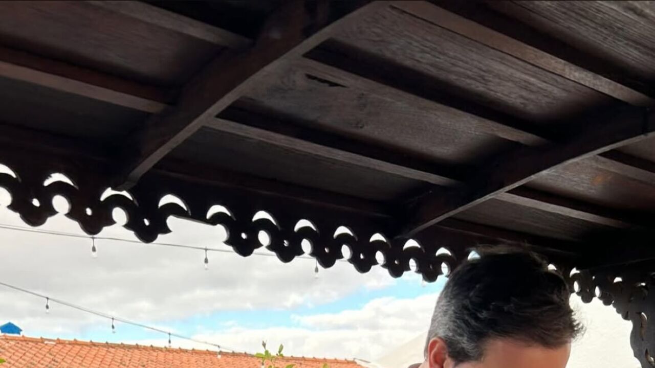 Um casal a preparar bebidas num bar ao ar livre.
