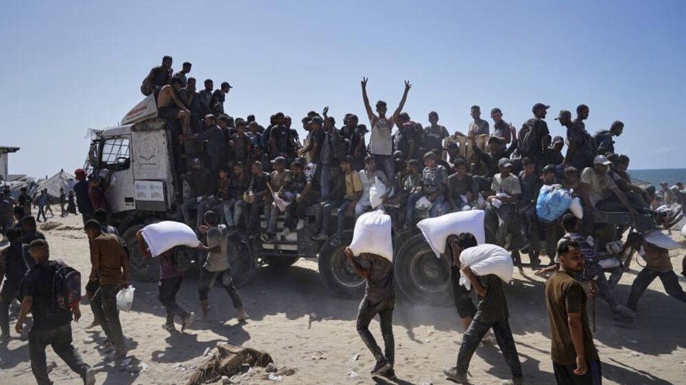 Palestinianos carregam bens perto do mar; Portugal poderá reconhecer o Estado da Palestina