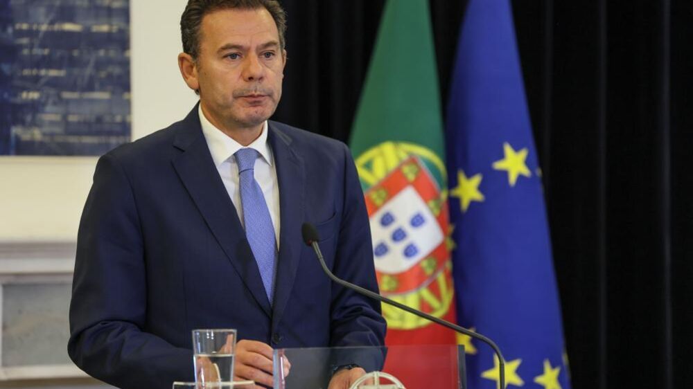 Figura pública discursa com as bandeiras de Portugal e da União Europeia ao fundo