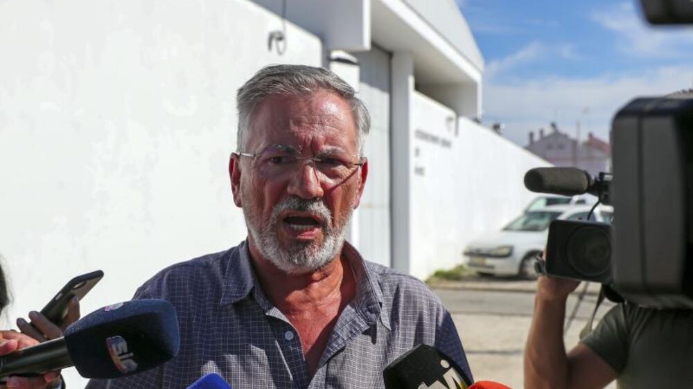 Homem discursa para microfones de órgãos de comunicação social