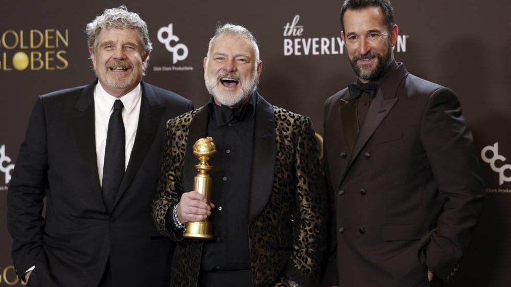 Os produtores John Wells e R. Scott Gemmill com o ator Noah Wyle exibem o troféu ganho por 'The Pitt' 