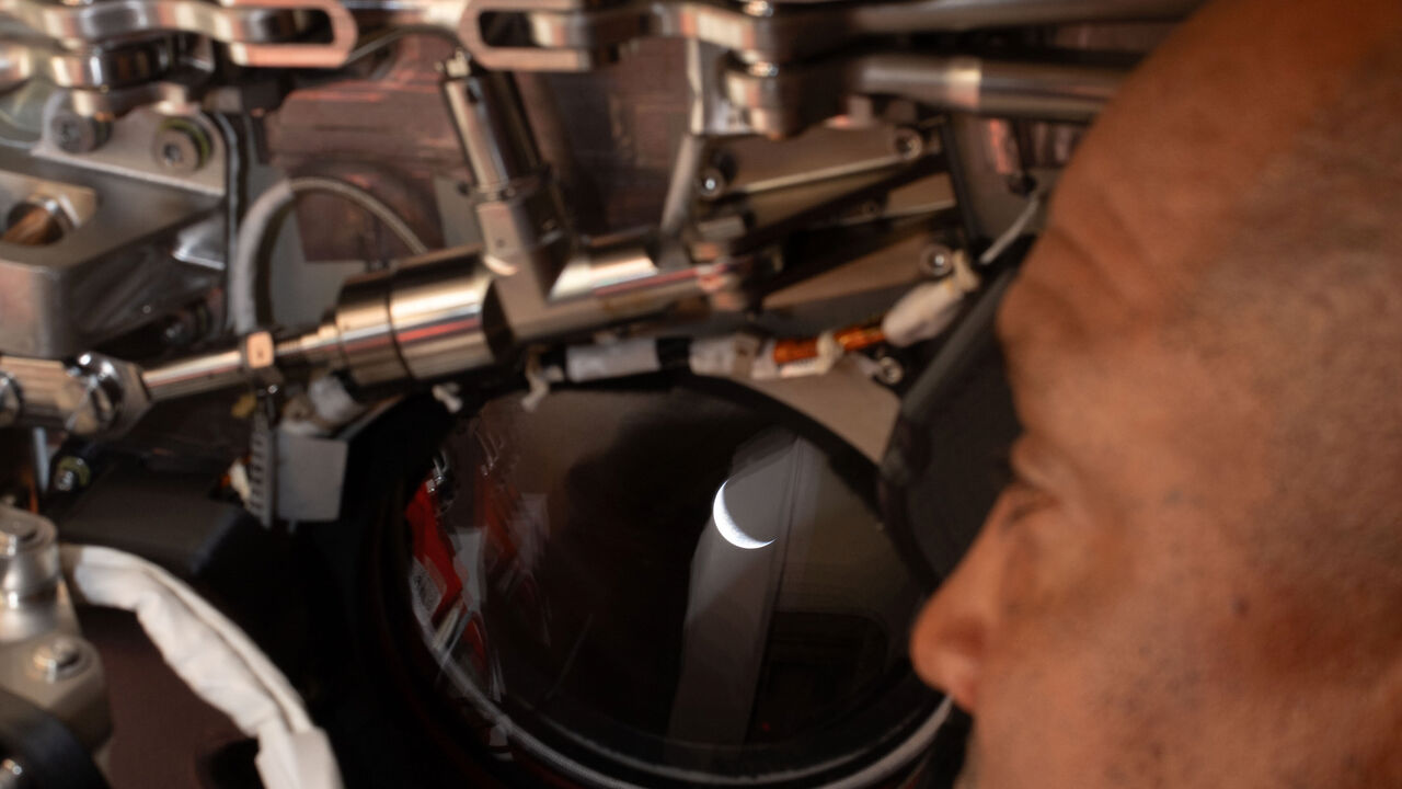 Victor Glover olha pela janela da nave espacial 