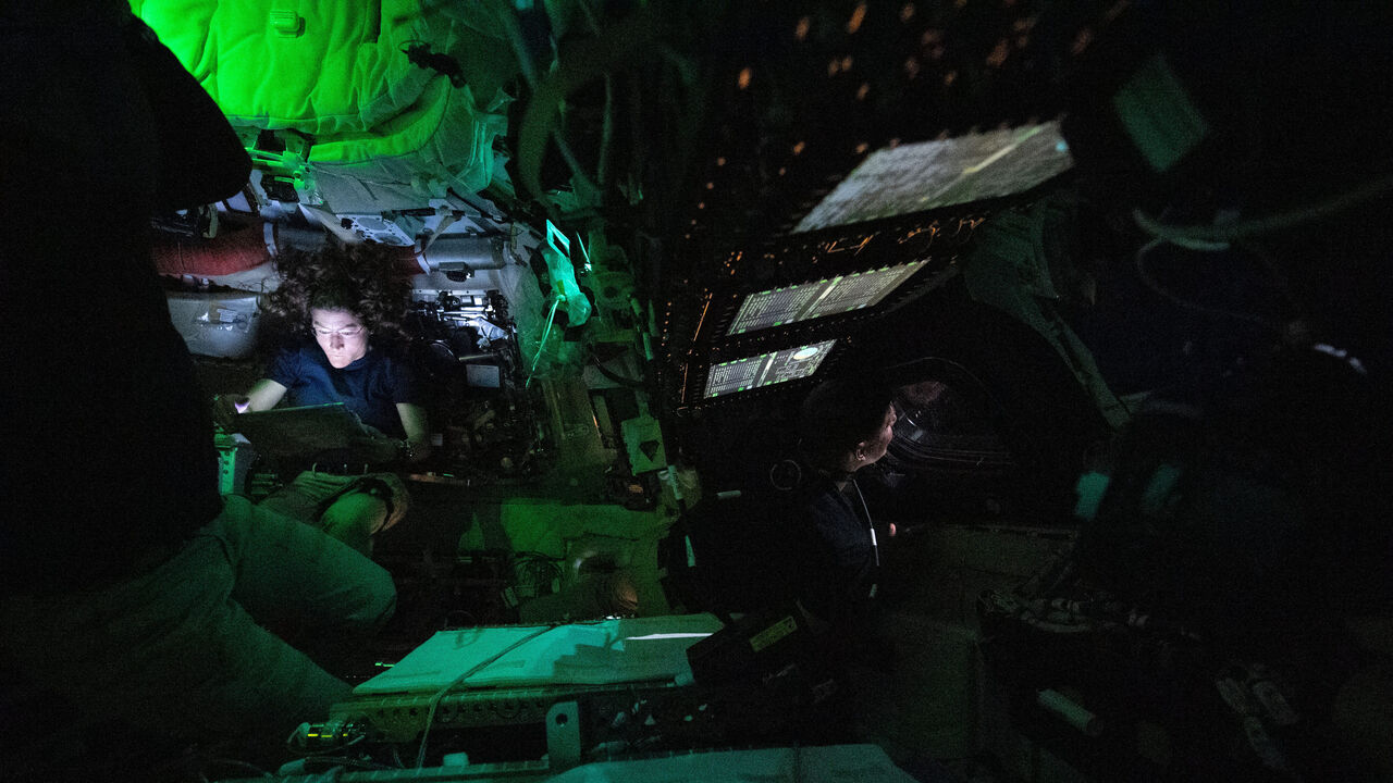 Astronauta Christina Koch é iluminada por um ecrã no interior da nave espacial
